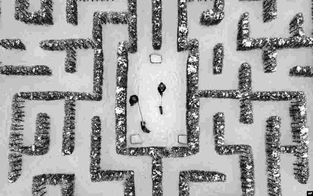 People walk with their dogs in a snow-covered Garden maze in Gelsenkirchen, Germany.