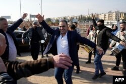 Men released from prison dance at the entrance of Aleppo city, on Dec. 9, 2024, as people wait for the return of relatives after the release of detainees from Syrian government prisons following the ousting of Syria's president.