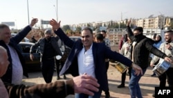 FILE - Men just released from prison dance at the entrance of Aleppo city, on Dec. 9, 2024, as people wait for the return of relatives after the release of detainees from Syrian government prisons following the ousting of Syria's president.