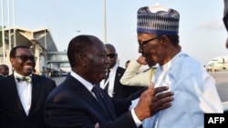 Le président nigérian Muhammadu Buhari, à droite, échange une accolade avec son homologue ivoirien, Alassane Ouattara, à son arrivée à l'aéroport Félix Houphouët-Boigny, à Abidjan, Côte d’Ivoire, 28 novembre 2017.