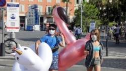 Tourists wearing protective face masks walk by a COVID-19 information sign in Nice as France reinforces mask-wearing as a part of efforts to curb coronavirus infections across the country, in Nice, France August 11, 2020. REUTERS/Eric Gaillard