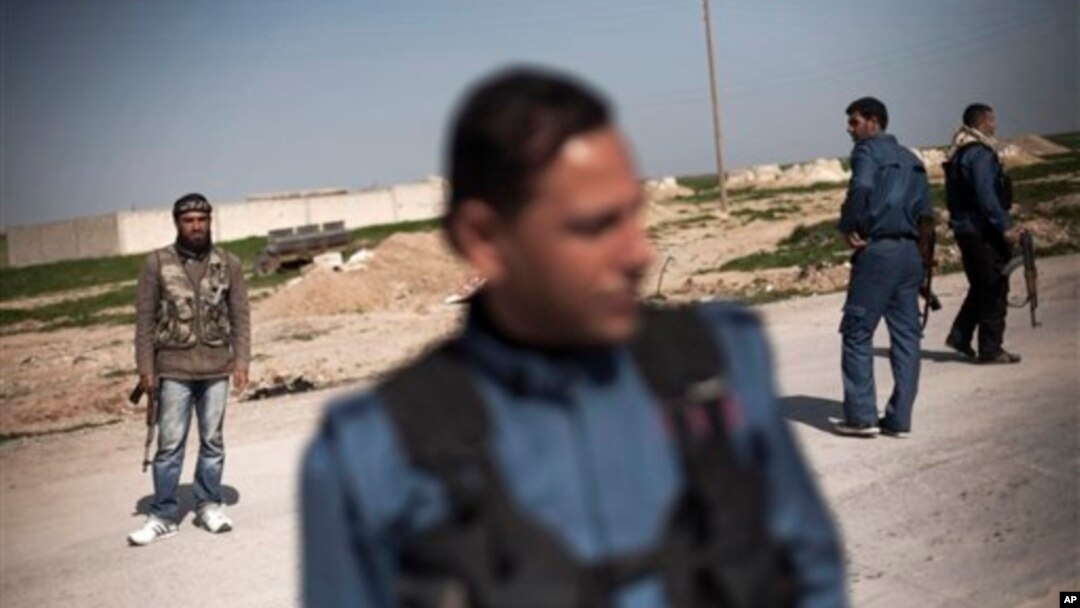 Members of a Kurdish militia and the Free Syrian Army rebels forces stand guard at a check point in Ras al-Ain on the border with Turkey, Feb. 27, 2013. Kurds now control the strategic town.