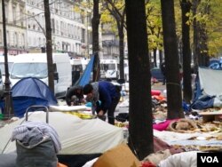 Local residents clear up the detritus of a dismantled tent camp in northern Paris, November 2016. (L.Bryant/VOA)