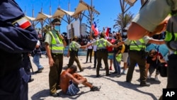 La policía chilena protege a un migrante venezolano que fue atacado por un manifestante que marchaba contra la migración ilegal, en una playa de Iquique, Chile, el 30 de enero de 2022. 