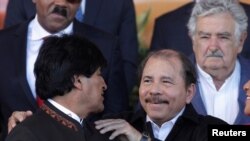 ARCHIVO - El presidente de Nicaragua, Daniel Ortega, a la derecha, saluda al exmandatario de Bolivia, Evo Morales, durante la foto de familia en la cumbre de la Comunidad de Estados Latinoamericanos y Caribeños (CELAC), en enero de 2015.