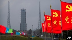 Flags with the logo of the Communist Party of China fly in the breeze near a launch pad at the Wenchang Space Launch Site in Wenchang in southern China's Hainan province, Monday, Nov. 23, 2020. (AP Photo/Mark Schiefelbein)