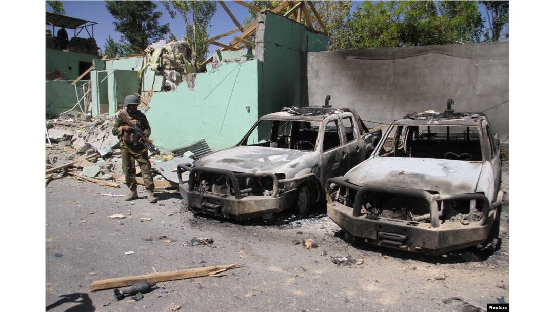 A member of the Afghan security forces stands guard next to damaged army vehicles after a Taliban attack in Ghazni city, Afghanistan, Aug. 15, 2018.