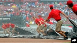 Members of the St. Louis Cardinals grounds crew pull the tarp over the infield as it rains during the first inning of a baseball game against the Minnesota Twins, in St. Louis, June 16, 2015.