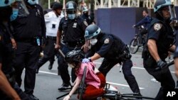 In this June 3, 2020 file photo, a protester is arrested by NYPD officers for violating curfew beside New York's iconic Plaza Hotel, following the death of George Floyd