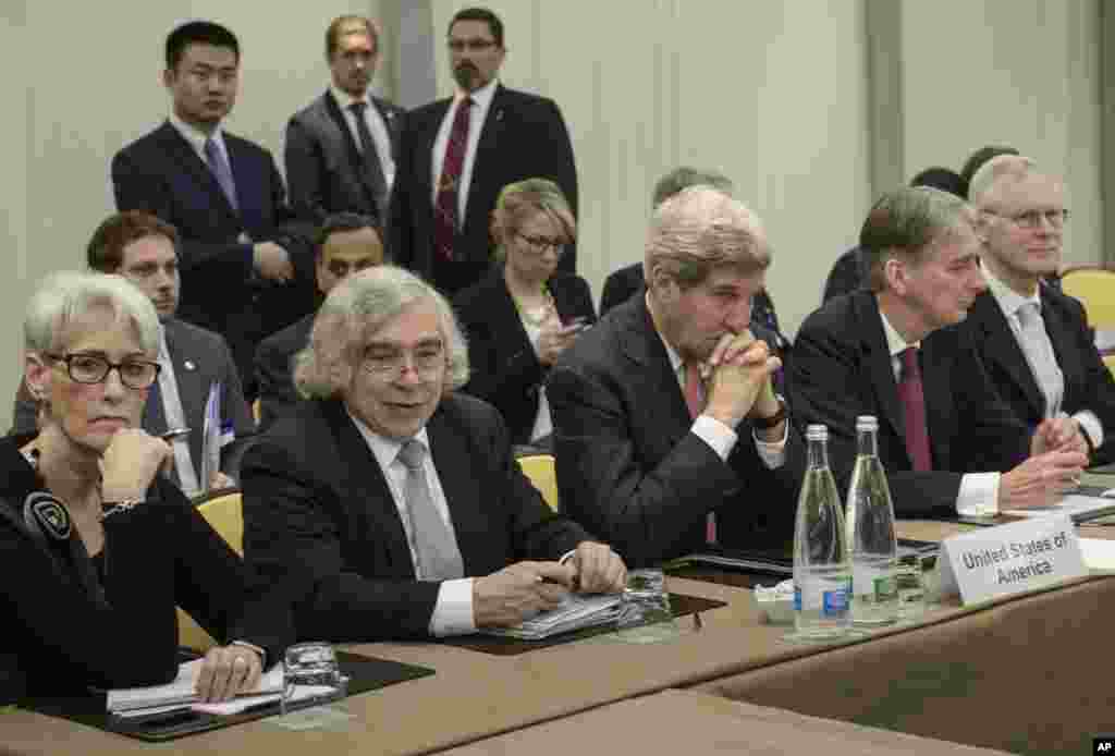 As the nuclear negotiation deadline approaches, U.S. Secretary of State John Kerry (center) and British Foreign Secretary Philip Hammond (second right) wait with officials from Russia, China, France, Germany, European Union and Iran at the Beau Rivage Palace Hotel in Lausanne, Switzerland, March 30, 2015.