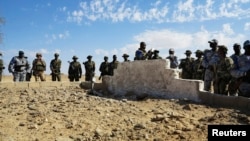 Malian and French soldiers stand next to a mass grave in Aguelhok, Mali, January 24, 2014.