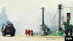 FILE - Photo shows Cambodian Buddhist monks (C) walking near a tank along a street in Phnom Penh, July 7, 1997. 