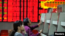 Investors look at computer screens in front of an electronic board showing stock information at a brokerage house in Hefei, Anhui province. Oct. 8, 2013.