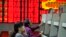 Investors look at computer screens in front of an electronic board showing stock information at a brokerage house in Hefei, Anhui province. Oct. 8, 2013.