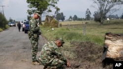 ARCHIVO - Soldados colombianos inspeccionan el lugar donde explotó una pequeña bomba dirigida a un autobús que transportaba personal de la Armada cerca del aeropuerto de Guaymaral, en Bogotá, Colombia, el 7 de marzo de 2016.