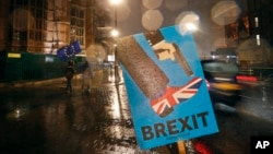 Vehicles drive past an anti-Brexit sign that is placed near the Parliament in London, Jan. 29, 2019.