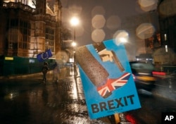 FILE - Vehicles drive past an anti-Brexit placard that is placed near the Parliament in London, Jan. 29, 2019.