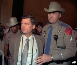 FILE - Texas Department of Public safety officers escort Louis Beam away from a March 18, 1993, Branch Davidian news briefing with the FBI and ATF in Waco, Texas.