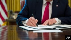 FILE - President Donald Trump signs an executive order to increase sanctions on Iran, at the White House, June 24, 2019, in Washington. Trump said Jan. 8, 2020, that Iran would face new sanctions in response to a missile attack on two Iraqi bases.