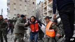 Tim penyelamat tampak membawa jenazah korban gempa dari reruntuhan bangunan yang ambruk dalam proses evakuasi di Aleppo, Suriah, pada 7 Februari 2023. (Foto: AP/Omar Sanadiki)