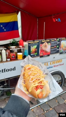 Su negocio es un carrito de hot dogs (perros calientes). Sin embargo, está inspirado en los sabores venezolanos y también en la forma en la que se venden en su país natal.