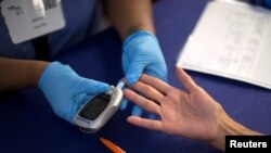 FILE - A person receives a test for diabetes at a free medical clinic in Los Angeles, California, Sept. 11, 2014. 