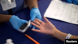 FILE - A person receives a test for diabetes at a free medical clinic in Los Angeles.