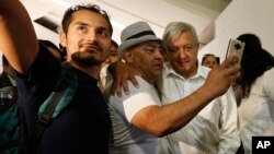 Mexican President Andres Manuel Lopez Obrador, center right, poses for selfies with travelers as he arrives for his commercial flight to Mexico City, at the airport in Guadalajara, Mexico, March 9, 2019.