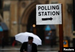 A man carries an umbrella past a polling station for the Referendum on the European Union in central London, Britain, June 23, 2016.