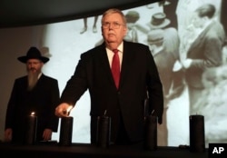 FILE - U.S. Ambassador to Russia John Tefft lights a candle at a ceremony marking the International Holocaust Remembrance Day in the Jewish Museum and Tolerance Center in Moscow, Russia, Jan. 27, 2017. At left is Russia's chief rabbi, Berel Lazar.