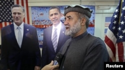 Afghan journalist Abdul hai Warshan talks during an interview in front of cardboard cut-outs of U.S. President Barack Obama and Republican presidential candidate Mitt Romney at the U.S. embassy in Kabul, November 7, 2012.
