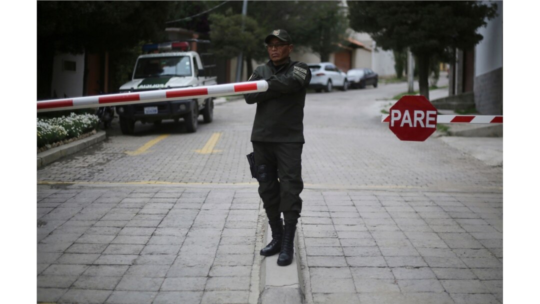 A police officer guards the gate to the residence of Mexico's ambassador to ensure 9 ex-officials from the government of deposed Bolivian President Evo Morales, who have taken refuge inside, don't leave the country, in La Paz, Bolivia, Dec. 30, 2019.