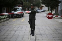 A police officer guards the gate to the residence of Mexico's ambassador to ensure 9 ex-officials from the government of deposed Bolivian President Evo Morales, who have taken refuge inside, don't leave the country, in La Paz, Bolivia, Dec. 30, 2019.