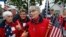 FILE - The Freeport Flag Ladies, Carmen Footer, from left, JoAnn Miller and Elaine Greene, wave to vehicles in Freeport, Maine, Aug. 23, 2011.