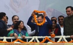 Incumbent Delhi Chief Minister Arvind Kejriwal, center, is garlanded at Aam Aadmi Party, or "common man's" party headquarters as they celebrate the party's victory in New Delhi, India, Feb. 11, 2020.