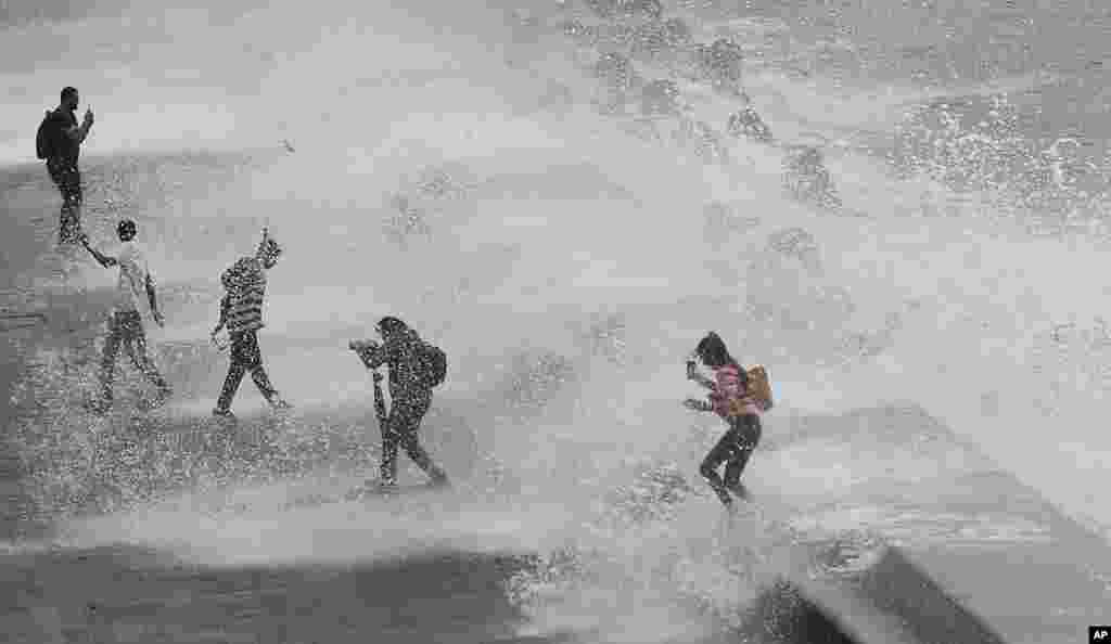 People are drenched by waves during high tide by the Arabian Sea in Mumbai, India.