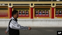 A man walks past portrait of communist party members on display outside Imperial Ancestral Temple in Beijing, China, November 12, 2012.