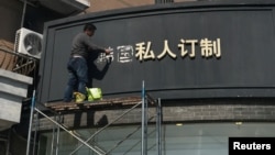 FILE - A worker removes part of a sign that consists of the Chinese characters that collectively read South Korea, at a shop in Shanghai, China, March 15, 2017