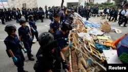 Polisi membongkar barikade yang dipasang para demonstran pro-demokrasi di luar kantor-kantor pemerintahan di Hong Kong (11/12). (Reuters/Liau Chung-ren)