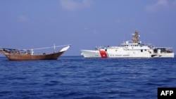 A handout picture released by the US Central Command (CENTCOM) on February 15, 2024, shows a US navy cutter next to a vessel reportedly carrying a shipment of Iranian weapons destined for Yemen's Huthi rebels which was seized on January 28.
