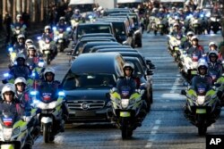 FILE - A motorcycle parade follows the hearse carrying the casket of French rock star Johnny Hallyday, down the Champs-Elysees avenue in Paris, Saturday, Dec. 9, 2017.