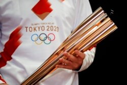 Penyanyi Yunani Sakis Rouvas mengenakan seragam pelari estafet Olimpiade di Athena, Yunani, saat memegang obor Olimpiade Tokyo 2020, 24 Februari 2020. (Foto: dok).