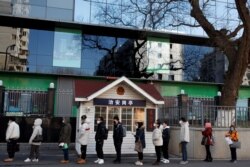 FILE - People line up to register their temperature and personal details as they arrive for work at an office building in Beijing, China, March 3, 2020.