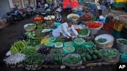 A roadside vendor arranges vegetables at his shop early in the morning in Ahmadabad, India, Dec. 29, 2015. 