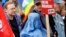 FILE - A protester dressed in traditional burqa garment attends a demonstration against the deployment of German armed forces in Afghanistan in front of the Brandenburg Gate in Berlin.