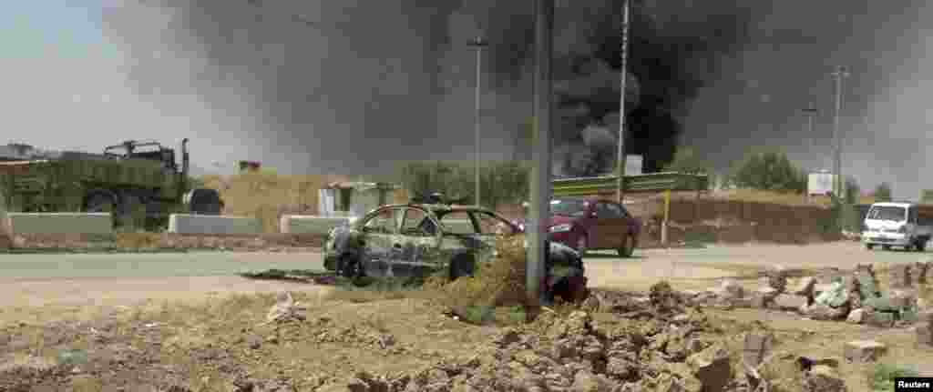 A burnt vehicle belonging to Iraqi security forces is seen on a road one day after insurgents seized control of the city of Mosul, June 10, 2014.