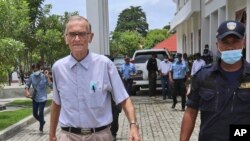 Seorang polisi mengawal Richard Daschbach (kiri), mantan misionaris Pennsylvania, menuju ruang sidang di pengadilan Oecusse, Timor Leste, 23 Februari 2021. (AP Photo / Raimundos Oki)