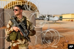 FILE - A French airman stands guard near a Hartford drone, at the Niamey military base, in Niger.