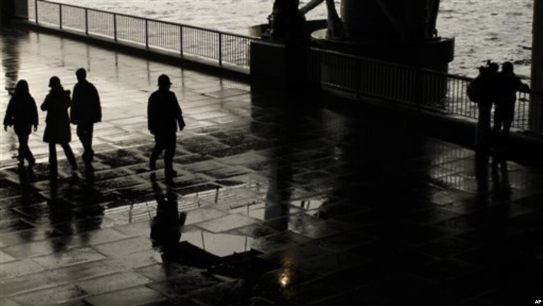 A patrolling police officer, center, is silhouetted under a bridge on the South Bank by the River Thames as he looks over at an embracing couple after a rain shower in London, 7 Jan 2011