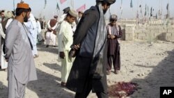 Afghans look at a pool of blood at the scene of an explosion at a cemetery in Lashkar Gah southwest of Kabul, Afghanistan, August 19, 2012.